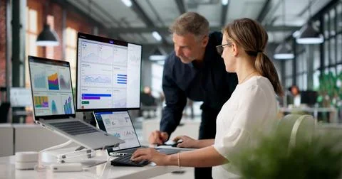 Two Financial Analysts Working Together, Reviewing Data On Dashboard. Stock Photos