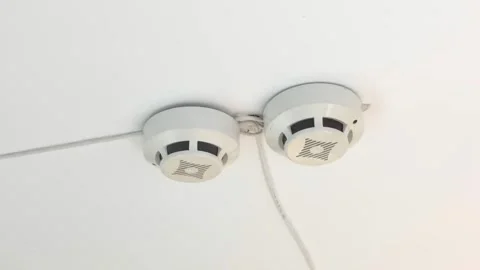 Two fire safety detectors mounted on a white ceiling in closeup Stock Footage 326215766