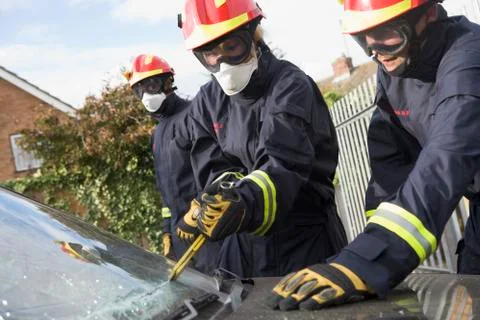 Two firefighters cutting out a windshield after an accident with another Stock Photos