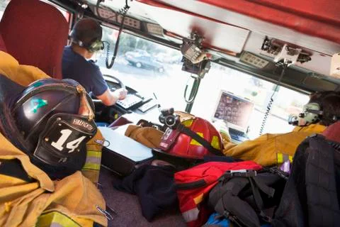 Two firefighters driving a fire engine with gear in the back (selective focus) Foto stock