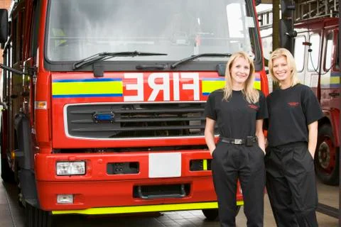 Two firefighters standing in front of fire engine Stock Photos