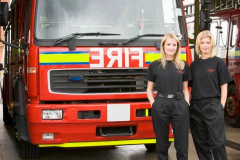 Two firefighters standing in front of fire engine Stock Photos
