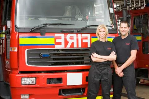 Two firefighters standing in front of fire engine Stock Photos