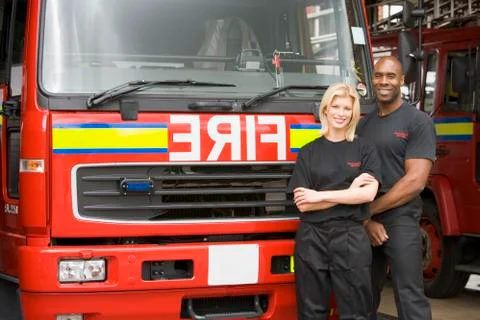 Two firefighters standing in front of fire engine Stock Photos