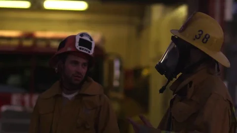 Two firefighters talk outside the firehouse. Stock Footage 69175434