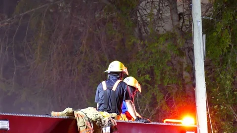Two firefighters on top of firetruck Stock Footage 116015445