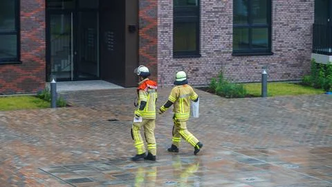 Two firefighters walking in front of modern building Stock Photos