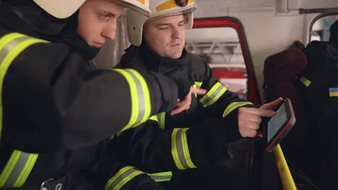 Two firemen analysing data looking on digital tablet in the truck cabin Stock Footage 153068258