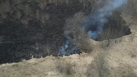 Two firemen extinguish a fire. Burning field. Wildfire in the mountains. Stock Footage 270208781
