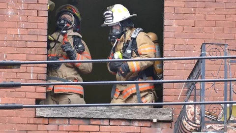 Two firemens talking to each other through a window hole Stock Footage 89522874