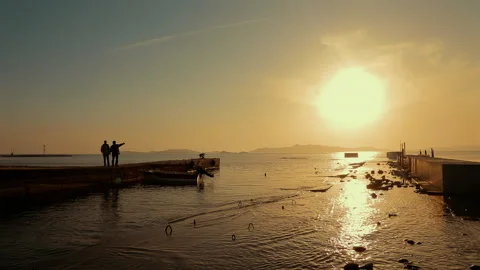 Two fishermen are talking while standing on the pier at sunset. Stock Footage 247772627