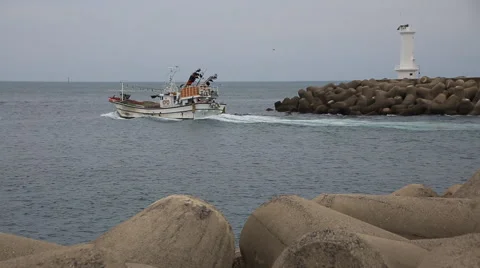 Two fishing boats intersecting by the white lighthouse behind sea walls Stock Footage 59160593