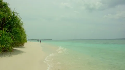Two fishmen walking along the ocean coastline against the backdrop of the sea wa Video stock 121682105