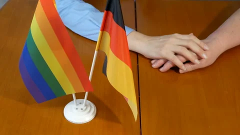 Two flags Germany and lgbt and woman hands on wooden table Stock Footage 163573270