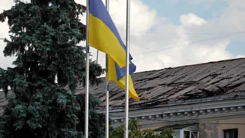 Two flags of Ukraine against the background of a damaged house Stock Footage 248725007