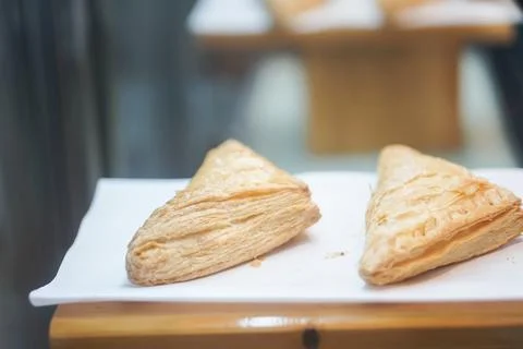 Two flaky triangular puff pastries on a white board Stock Photos