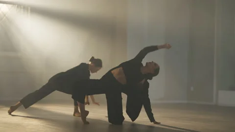 Two flexible graceful slim ballet dancers rehearsing in backlit fog in studio Stock Footage 158714712