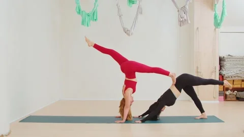 Two flexible women practicing acrobatics and balance yoga in the room 库存影片 214928961
