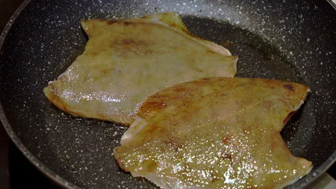 Two flounder were fried in a pan. A cook is frying fish in a home kitchen. Stock Footage 277452100