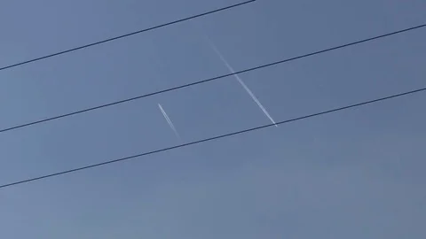 Two flying jets crossing power lines, blue sky, bird flying by Stock Footage 76765277