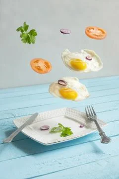 Two flying levitated fried eggs, tomats and punch Stock Photos