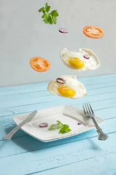 Two flying levitated fried eggs, tomats and punch Stock Photos