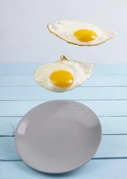 Two flying levitated fried eggs on blue backgrounds Stock Photos