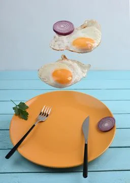 Two flying levitated fried eggs on blue backgrounds Stock Photos