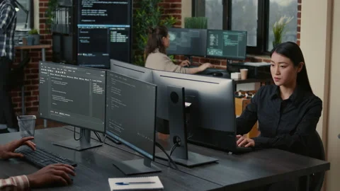 Two focused coders facing each other writing code in software development office Stock Footage 168248496
