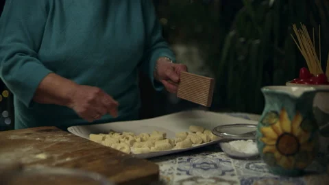 Two focused Italian cooks rolling out dough and forming pillows for gnocchi for Stock Footage 199459657
