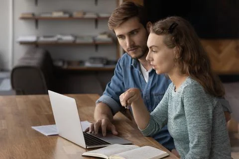 Two focused students discussing learning task at laptop Stock Photos