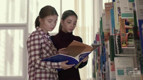 Two focused university students choosing books for their research Stockbeeldmateriaal 73312577