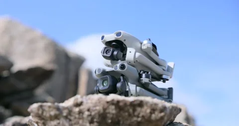 Two Folded Grey Drones Stacked on Top of Each Other on a Rock Stock Footage 347807013
