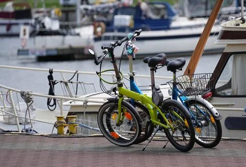 Two folding bicycles parked on the jetty for yacht by the sea. Stock Photos