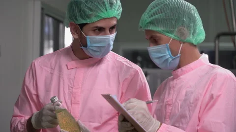 Two food scientist worker wearing hairnet and face mask discussing while chec Stock Footage 142698880