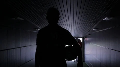 Two football players are walking along a dark tunnel to the football field. View Stock Footage