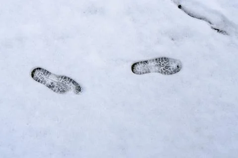 Two footprints in the snow, one on the left and one on the right Stock Photos