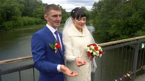 TWO FRAMES. Lovers lock the locks on fence and throw key in river to be lost Stock Footage 76431232