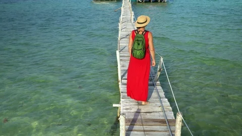 Two frames in video. Beautiful woman walking down pier in long red dress. Phu Video stock 87517513