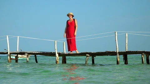 Two frames in video. Beautiful woman walking down pier in long red dress. Phu Stock Footage 87518862