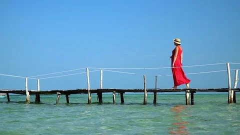 Two frames in video. Beautiful woman walking down pier in long red dress. Phu Video stock 87526633