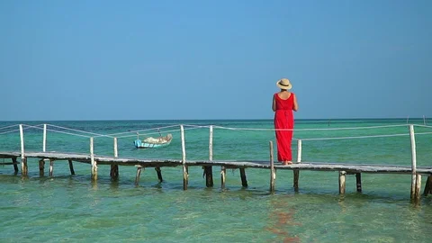 Two frames in video. Beautiful woman walking down pier in long red dress. Phu Video stock 87528185