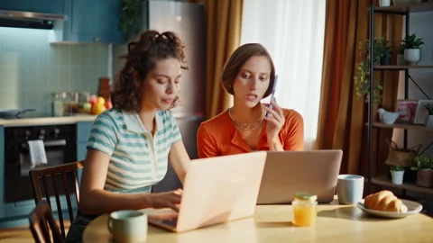 Two freelancers calling mobile phone looking laptops at home kitchen closeup. Stock Footage 333790977