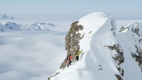 Two freeride skiers ascending a summit in Swiss Alps on a backcountry ski trip Stock Footage 129086082