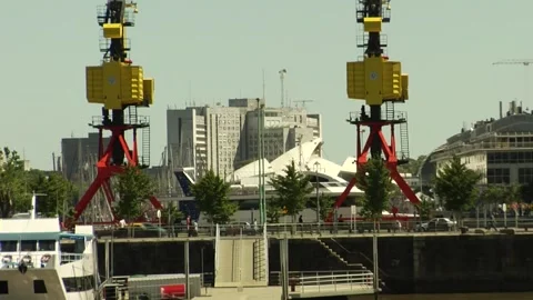 Two freight ship cranes and traffic in front of some city buildings. Stock Footage 160280625