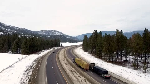 Two freight trucks pass through this overhead shot around curve with snow, tr Stock Footage 124713898