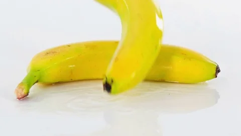 Two fresh bananas fall down on a table in the kitchen Stock Footage