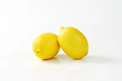 Two fresh bright yellow lemons on surface Stock Photos