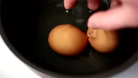 Two fresh brown eggs in a dark saucepan with cold water Stock Footage 179921230