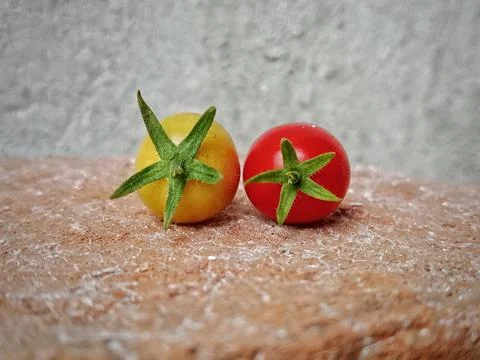 Two fresh cherry tomatoes on a textured brick Stock Photos
